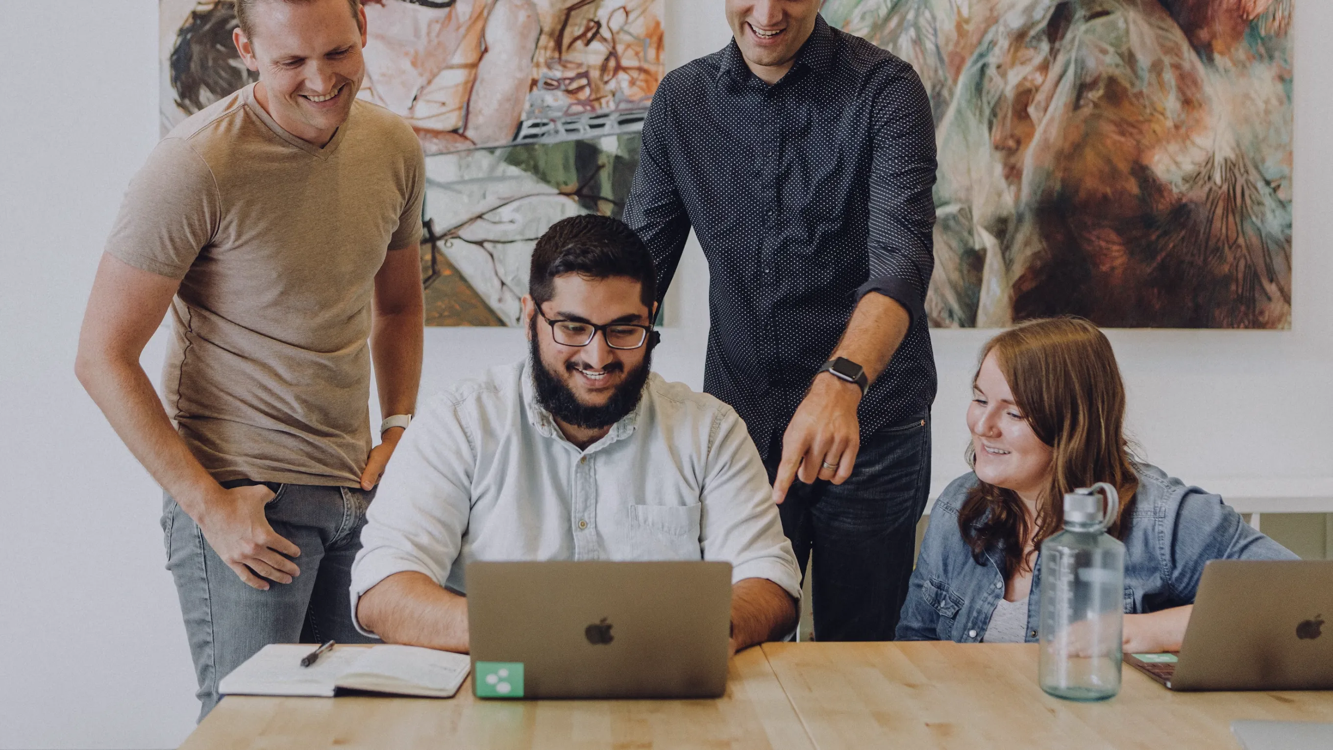 Equipo colaborando alrededor de un laptop